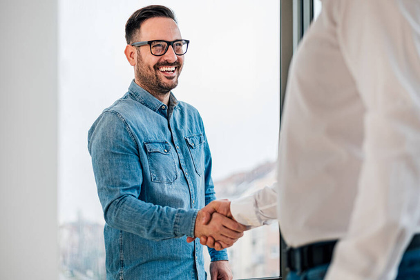 Businessman greeting job applicant businessmen handshaking over signed contract handsome entrepreneur handshake with a colleague cheerful young manager handshake with new employee getting a deal done - Photo, Image