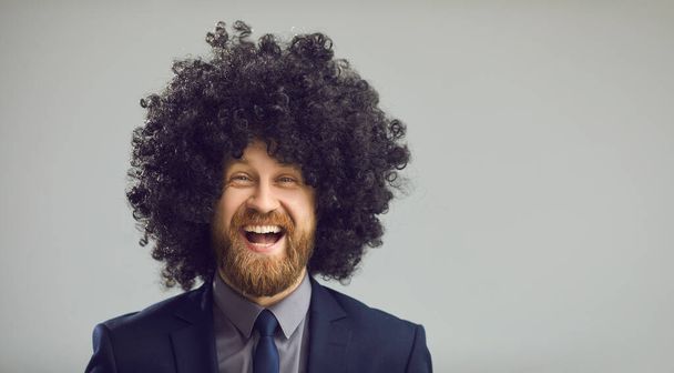 Gray copy space banner with portrait of funny laughing man in suit and crazy curly wig - Foto, Imagem
