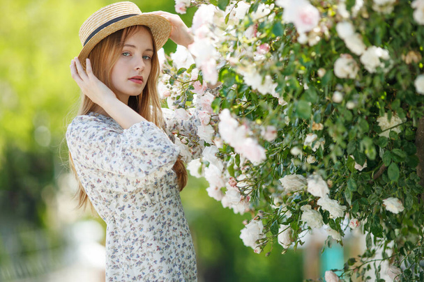 Hermosa chica en rosas en la naturaleza. Mujer joven con flores. - Foto, imagen