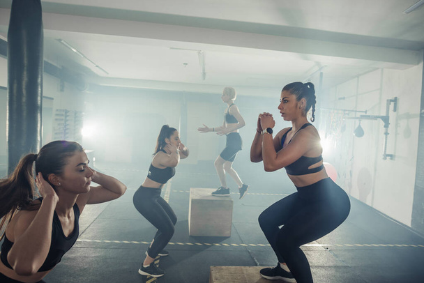 Ženská skupina s funkční fitness trénink dělat vestoje křupky a zvýšit ve sportovní tělocvičně - Fotografie, Obrázek