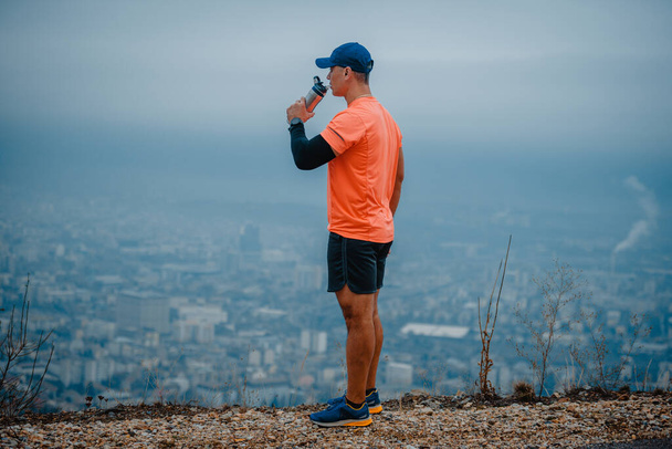 Well built middle aged athlete drinking water and taking a break from running - Photo, Image