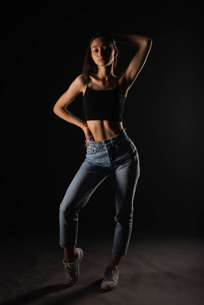 Casual dressed and beautiful girl is making a seductive pose in studio - Zdjęcie, obraz