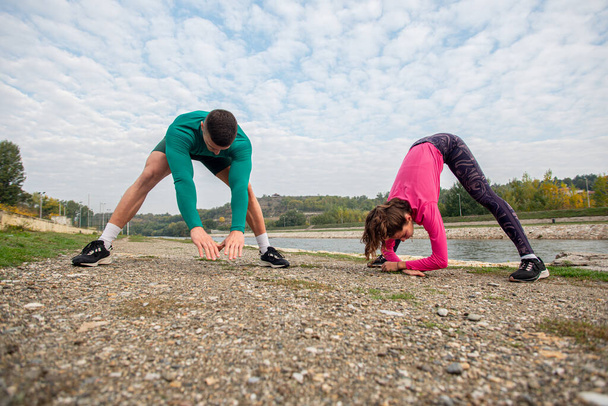 Beautiful couple is stretching and warming up together before their training - Fotoğraf, Görsel