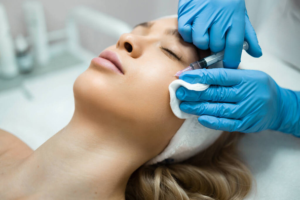 Woman getting cosmetic injection of botox in cheek. Anti-aging procedure and face lift in cosmetology clinic - Photo, Image