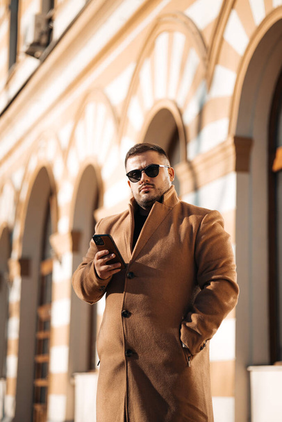portrait of handsome young man in sunglasses and jacket with mobile phone outdoors  - Φωτογραφία, εικόνα