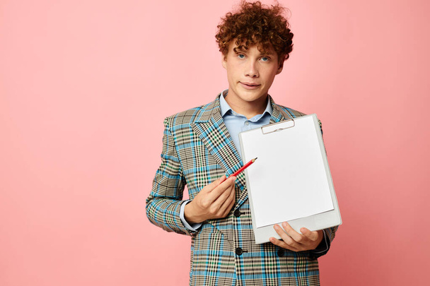 Young curly-haired man in a plaid jacket copy-space folder pink background unaltered - Photo, image