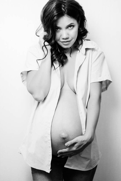attractive pregnant woman in jeans and a shirt on a naked body. womens health - Valokuva, kuva