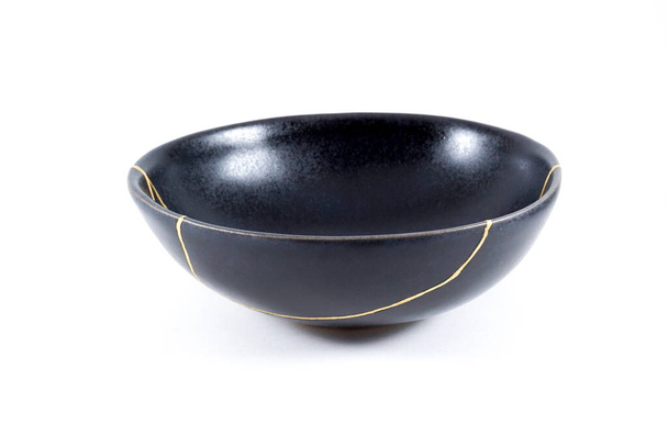 Gold cracks Kintsugi, broken black repaired bowl, Japanese technique. - Zdjęcie, obraz