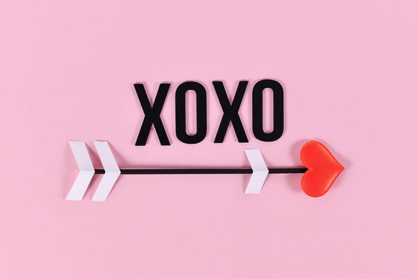 Valentine's day love arrow and XOXO text on pink background - Fotó, kép