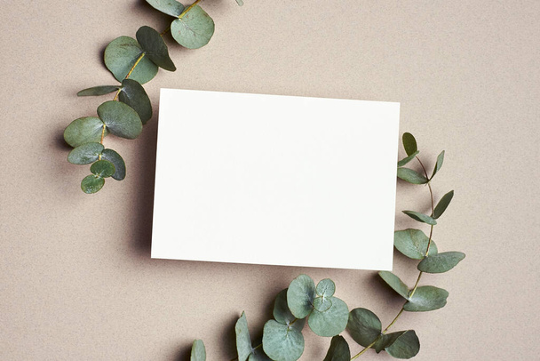 Greeting or wedding invitation card mockup with natural eucalyptus twigs. Blank card with copy space. - Fotografie, Obrázek