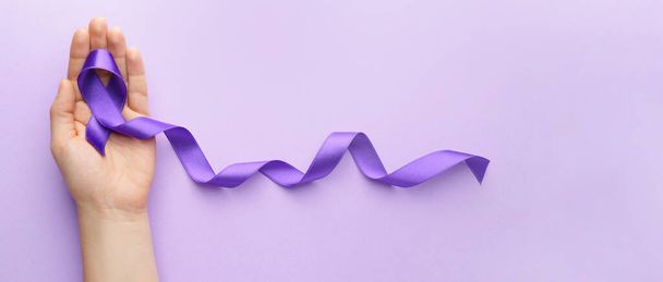 Female hand with purple ribbon on color background with space for text - Foto, immagini