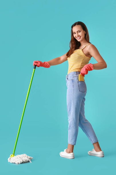 Young woman with floor mop on blue background - Fotoğraf, Görsel