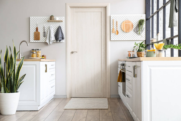 Интерьер современной кухни с белыми столешницами, дверными и колышками - Фото, изображение