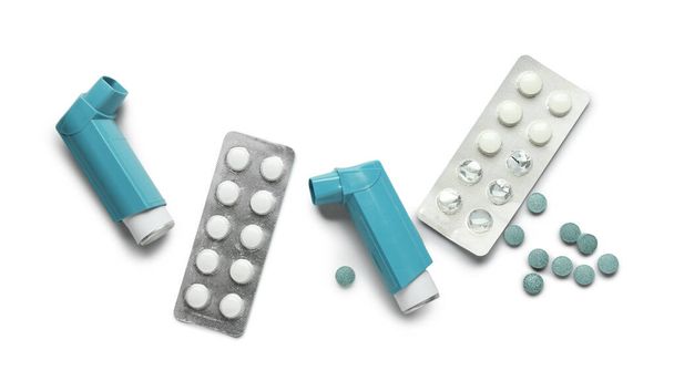 Modern asthma inhalers and blister packs of pills on white background - Zdjęcie, obraz