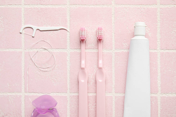 Zahnseide mit Zahnstochern, Bürsten und Paste auf rosa Fliesen Hintergrund - Foto, Bild