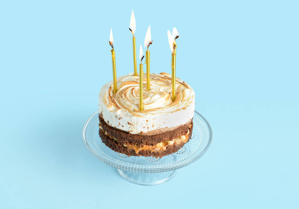 Підніміться зі смачним тортом на день народження та спалюючими свічками на синьому фоні
 - Фото, зображення