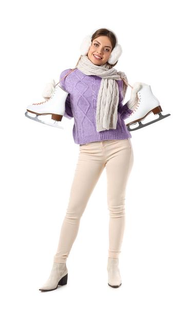 Gyönyörű fiatal nő téli ruhákban és korcsolyával fehér háttér - Fotó, kép