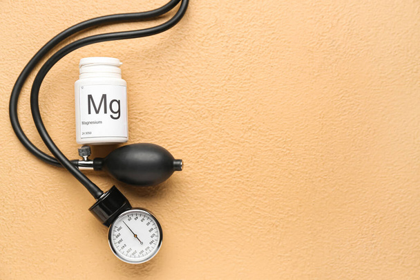 Frasco de pastillas de magnesio y esfigmomanómetro sobre fondo de color - Foto, imagen