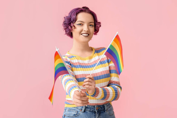 Młoda kobieta z flagami LGBT na różowym tle - Zdjęcie, obraz