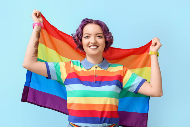 Junge Frau mit LGBT-Flagge auf blauem Hintergrund - Foto, Bild