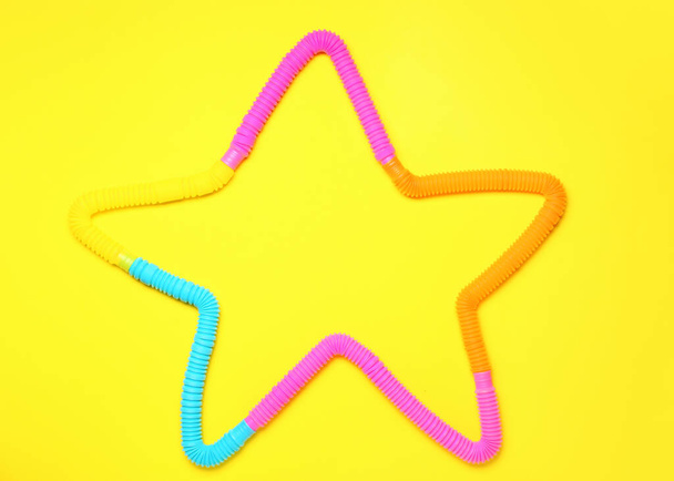 Star made of Pop Tubes on yellow background - Fotó, kép