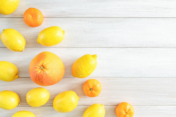 Fresh full grapefruit, tangerines and lemons on a white wooden background. Top view. Ripe and tasty citrus fruit. Copy space - Foto, Imagem