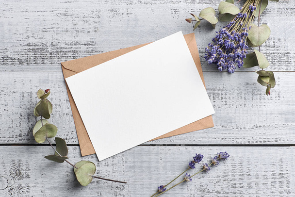 Greeting or invitation card mockup with dry lavender and eucalyptus on wooden background - Foto, Imagen