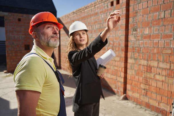 Woman describing builder her idea for house wall - Fotó, kép