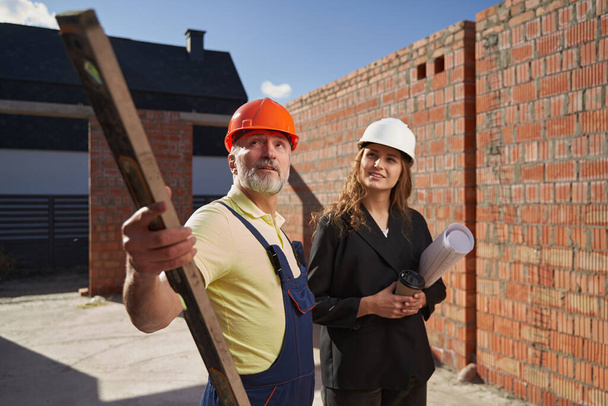 Male builder with pointing with bubble level - Foto, imagen