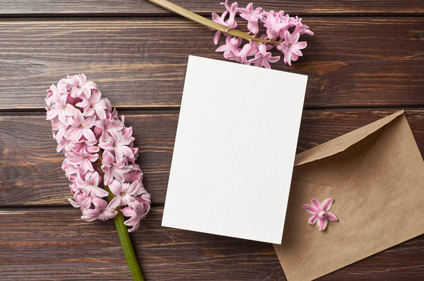 Invitation or greeting card mockup with envelope and hyacinth flowers on dark wooden background - Foto, Imagem