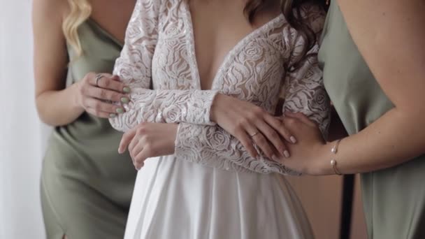 Bruid vriendinnen bruidsmeisjes in helpt de vrouw aan te trekken trouwjurk, hand vasthouden, knuffelen, omarmen - Video