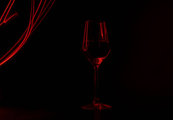 Champagne glass illuminated with red light painting on black background - Фото, зображення