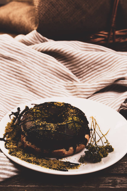 Delicious donut with chocolate sauce and pistachio nut pieces. - 写真・画像