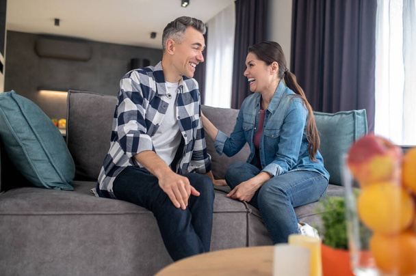 Happy laughing man and woman sitting on sofa - Photo, image