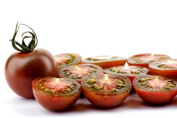 Hele en gesneden tomaten op een witte achtergrond. Zwarte tomaten. Cumato tomaten. - Foto, afbeelding