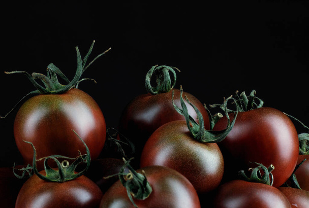 A few beautiful black tomatoes on a black background. Cumato tomatoes. - Fotoğraf, Görsel