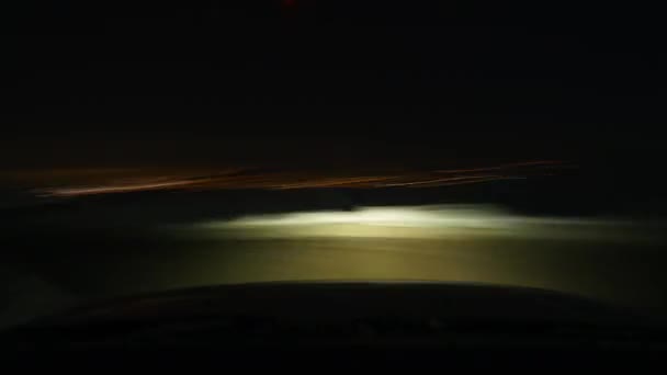 8K Car driving on snowy mountain road at night.Narrow mountain road between ski resort and city lights in winter.Rough dirt road.8K 7680x4320 4320p time lapse.Fast car travel with low shutter speed. - Felvétel, videó