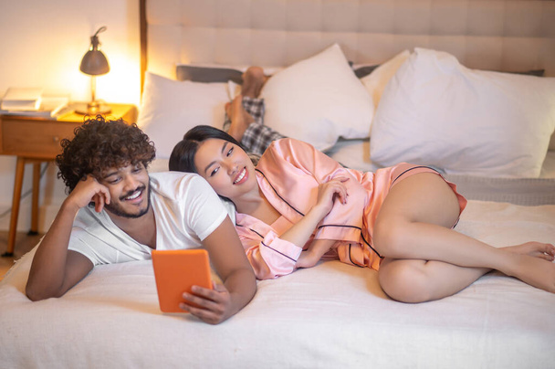 Woman leaning on man lying with tablet - Photo, Image