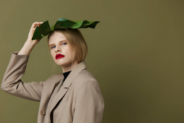 glamorous woman in coat red lips fashion palm leaf green background - Valokuva, kuva