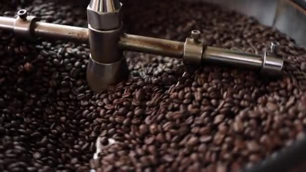 The process of roasting a batch of high quality single origin coffee beans in a large industrial roaster the toasted beans are in the cooling cycle. - Video