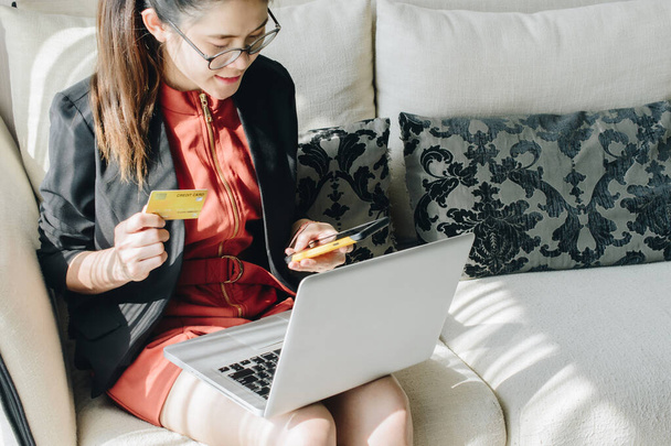 Portret van een zakenvrouw met een creditcard tijdens het gebruik van een laptop voor online winkelen. Online winkelen is het proces van het kopen van goederen en diensten van handelaren via het internet. - Foto, afbeelding