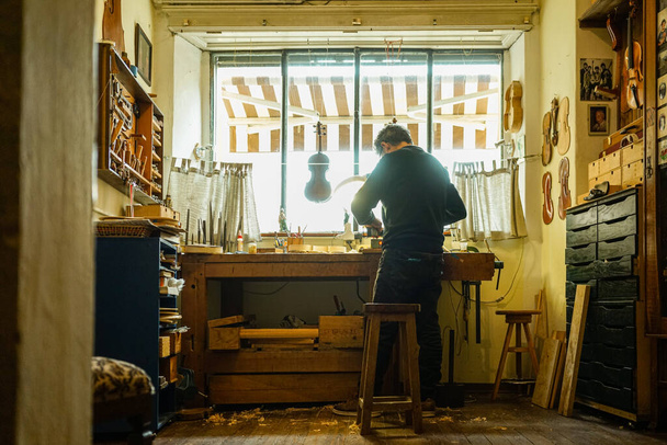 man in a black jacket with a beard and a tattoo in the workshop - Fotoğraf, Görsel