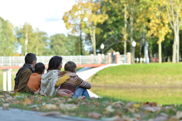 Szczęśliwa rodzina siedzący w parku jesień - Zdjęcie, obraz