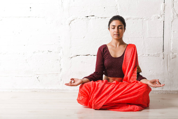 Junge erwachsene indische Frau in Sari meditierenden Yoga Lotus Pose Zen wie mit ok Zeichen Mudra Geste - Foto, Bild