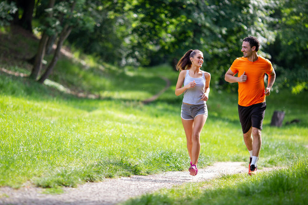 Happy couple running together in park - Фото, изображение