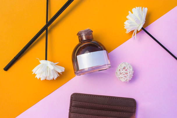 Frasco de perfume de 50 ml con etiqueta blanca en blanco y flor y billetera sobre fondo naranja-rosa. Perfume botella stock foto - Foto, Imagen