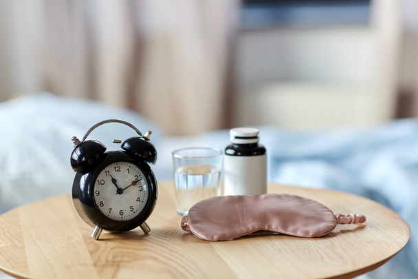 alarm clock, mask and sleeping pills on table - Photo, image
