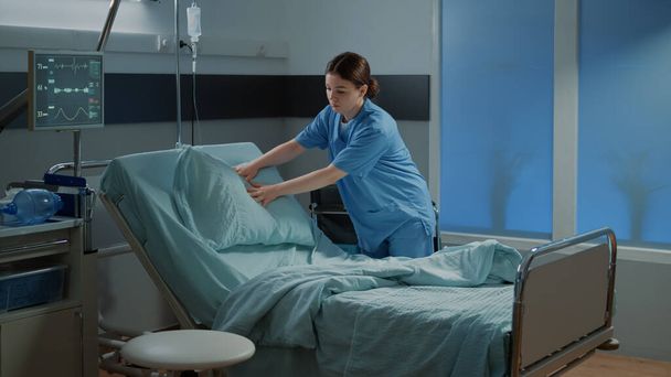 Медсестра готовит кровать и одеяло в палате больницы - Фото, изображение