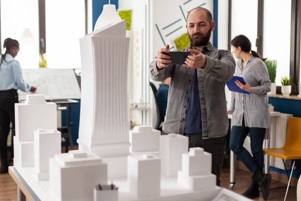 Építész dolgozik okostelefon fényképezni fehér hab skála modell - Fotó, kép