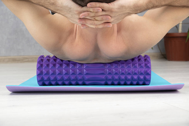 Чоловік робить масаж спини з міофасциальним роликом крупним планом. Міофасциальні м'язи спини. Вид ззаду
. - Фото, зображення